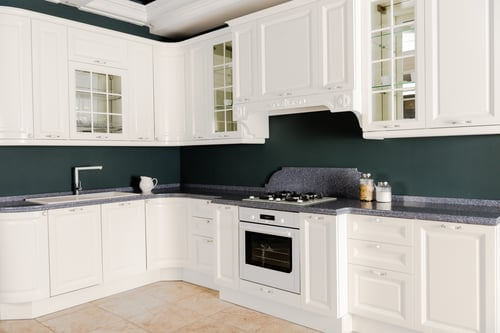 Refinished white kitchen cabinets against a deep green wall, refinished by AR Interiors Decoration Inc