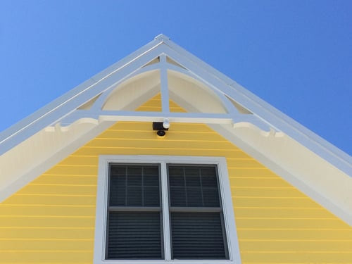 Freshly painted yellow exterior siding and white gable trim on a Central Florida home by AR Interiors Decoration Inc